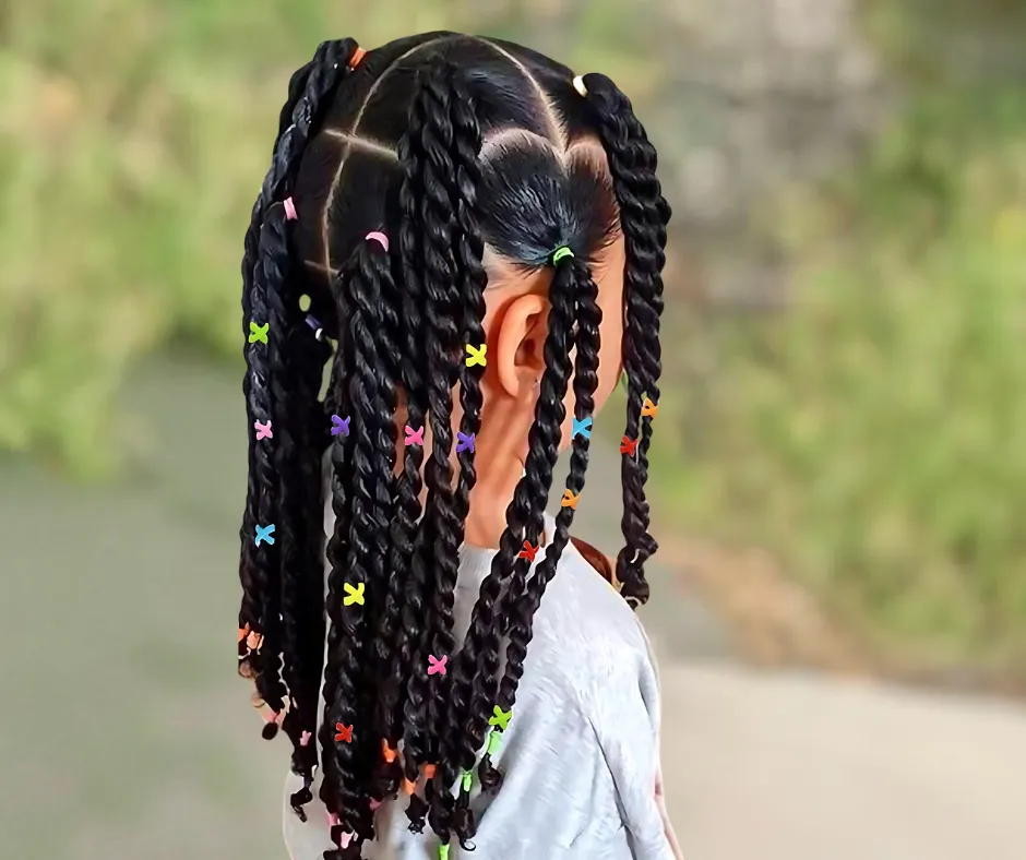 A young girl with twists styled into multiple sections, decorated with colorful hair ties, viewed from the back.