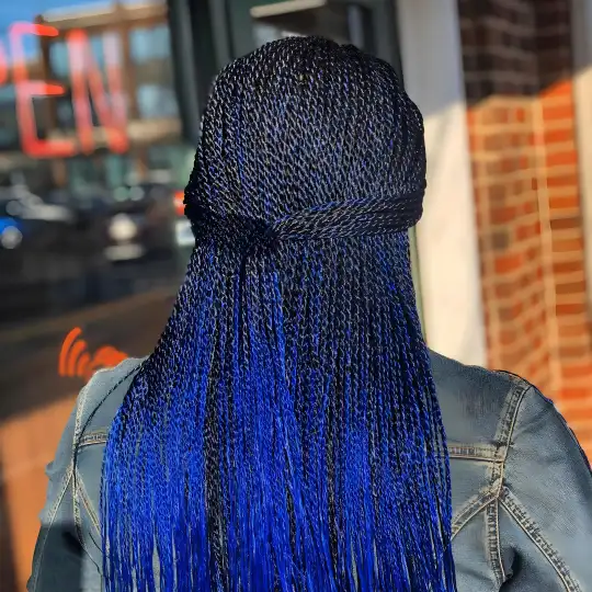 Client with long blue Senegalese twists standing outside Uniq Hair Braiding Salon.