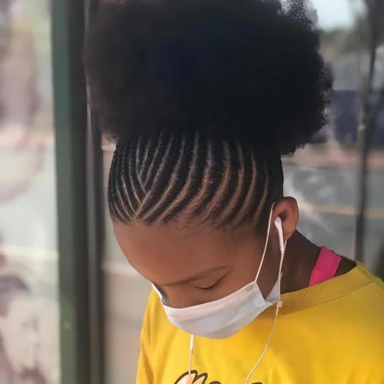 Client with cornrows leading into a natural afro puff at Uniq Braiding Salon.