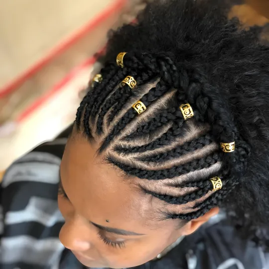 Close-up of cornrows with gold accessories on a client at Uniq Braiding Salon