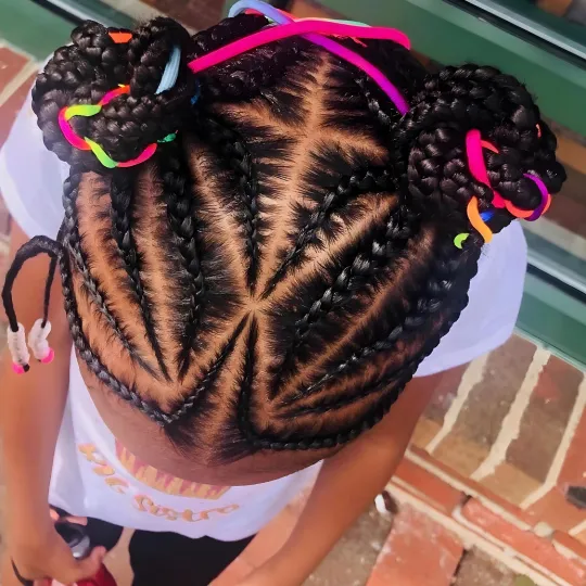 Top view of a child with intricate braids styled into two buns with colorful hair ties.