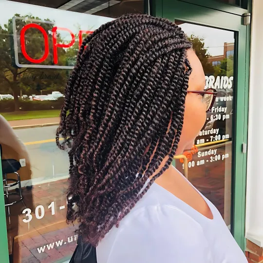 Woman with medium-length kinky twists standing outside a salon.