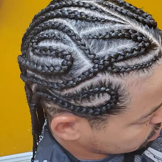 Man with intricate cornrow braids showcasing detailed patterns, viewed from the side.