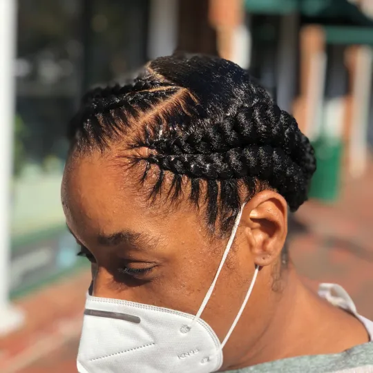 Woman with wrapped French braids styled elegantly around her head, wearing a mask at Uniq Braiding Salon.