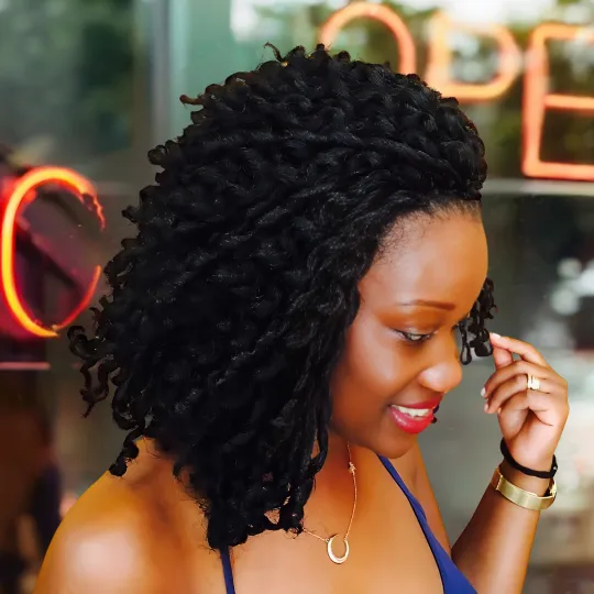 Woman with voluminous curly crochet hairstyle at Uniq Braiding Salon.
